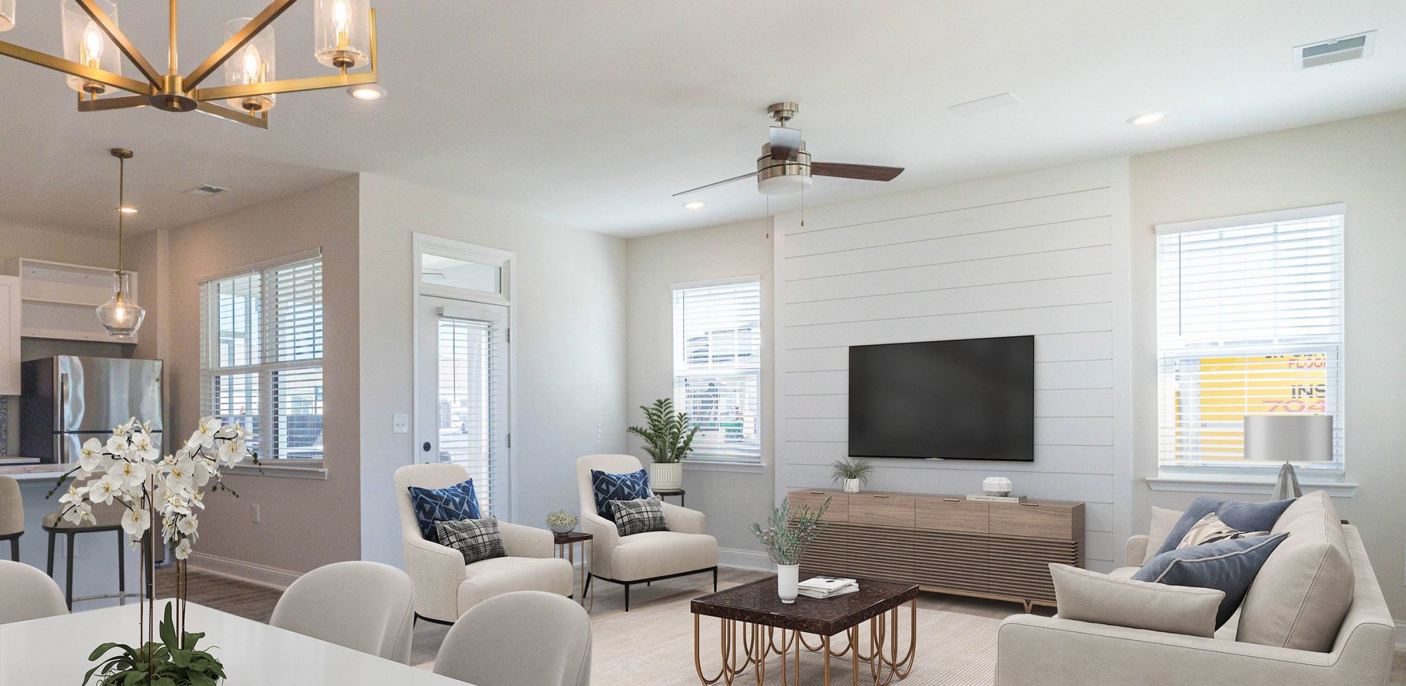 Hawthorne Cottages at Leland spacious living room with ceiling fan, couch, two chairs, coffee table, and TV mounted in cottage home wall