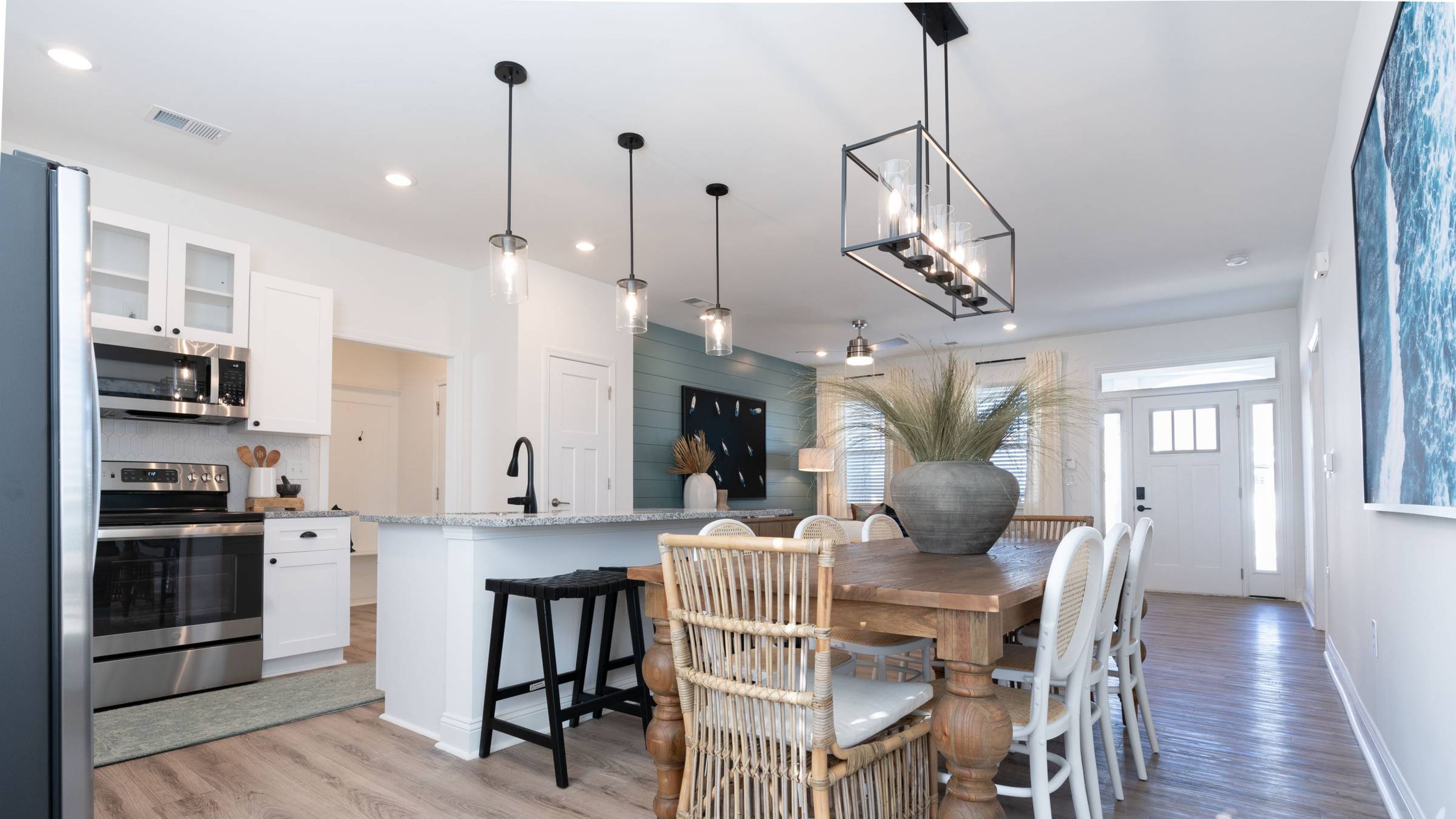 Hawthorne Cottages at Leland open-plan dining and kitchen area with a wooden dining table, wicker chairs, and elegant pendant lighting.